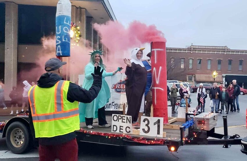Volunteer Russ Gant, foreground, waves as the Freedom Patch Fireworks float passes by during the annual West Plains Christmas Parade. The parade, organized by the Greater West Plains Area Chamber of Commerce, is made possible through the efforts of many volunteers, from helping with parade lineup to directing floats around the square.