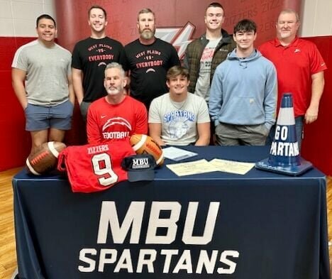 West Plains High School senior Isaiah Jones, quarterback for the Zizzer football team, seated right,has signed his commitment to attend Missouri Baptist University in Creve Coeur, where he intends to play football. He was joined for the occasion by fellow teammates and Zizzer Football coaches.
