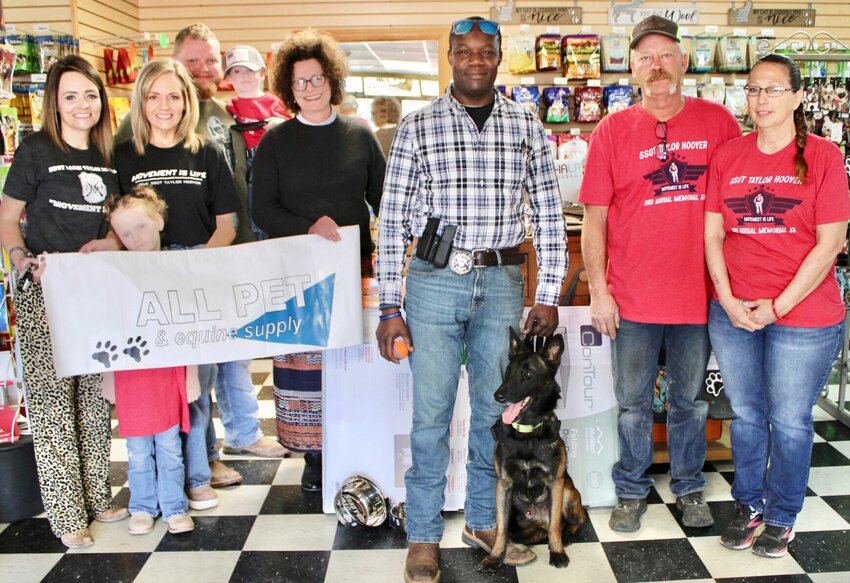 Locked and Loaded K9 and All Pet and Equine Supply, both in West Plains, have partnered with the Taylor Hoover Memorial Foundation to provide a service dog to veteran Carold Roberts, Jr., who served in the Marines for nine years and is now a Shannon County Deputy. From left are Hoover's sister Tori Manning and daughter Raelynn Manning; Hoover's mother Kelly Barnett; Tori&rsquo;s husband Thomas Manning, holding son Waylon; All Pet General Manager Phyllis Kupfer; Roberts; and Locked and Loaded K9 owners and trainers Daniel and Denise Parsons.