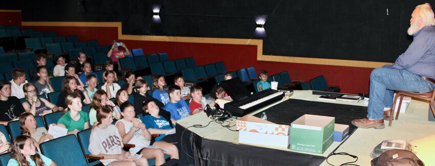 During a tour of downtown West Plains by students in Fairview teacher Erin Kimbrough’s summer school class, the youngsters heard some spooky history from West Plains mayor and local theater participant Mike Topliff, on the stage at right. When the group made a stop at the Avenue Theatre, Topliff talked about the ghostly cries of a baby that have been reported from the balcony, harkening back to the days when there was a “crying room” located near the projection booth for parents to calm their infants while not disturbing other patrons. Topliff expounded on what he’d heard through local lore about the downtown area, and his own experiences at the Catron Opera House at the corner of Court Square and West Main Street. The opera house was used as a morgue after the West Plains Dance Hall Explosion of Friday April 13, 1928, when 39 people were killed. Topliff talked about a “lady in white,” dressed in 1920s fashion, who is rumored to be searching for her dance partner. He told students he’d never seen the lady himself, but after he’d participated in an event there dressed as Santa Claus it seemed he’d been followed home by the mischievous spirit of a young girl that liked to rearrange household objects.