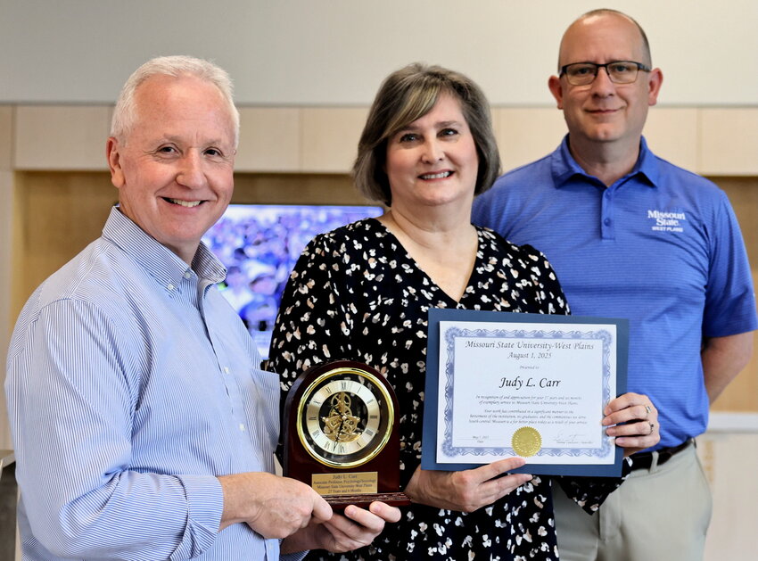 Judy Carr, center, associate professor of psychology/sociology at Missouri State University-West Plains will retire from her position Aug. 1 after 27 1/2 years as a full-time member of the faculty. Carr was hired as a per course faculty member in spring 1992 and joined the full-time faculty on Jan. 5, 1998, as instructor of Psychology/Sociology. She was promoted to assistant professor on Aug. 13, 2001, and was granted tenure on Aug. 12, 2002. She was promoted to her current rank on Aug. 13, 2012. In addition to teaching, Carr served as Faculty Senate chair from 2008-2009 and was on the Kids&rsquo; College planning committee for several years. She&rsquo;s received numerous awards during her career, including the Faculty Mentor Awards in 2007 and 2011, the Faculty Merit Award in 2012, the Governor&rsquo;s Award for Excellence in Education in 2015, and the West Plains Area Chamber of Commerce Educator of the Year in 2024. At a reception May 7, Carr received a certificate noting her years of service and a piano arch mantle clock from MSU-WP Chancellor Dennis Lancaster, left, and Vice Chancellor of Academic Affairs Dr. Michael Orf.