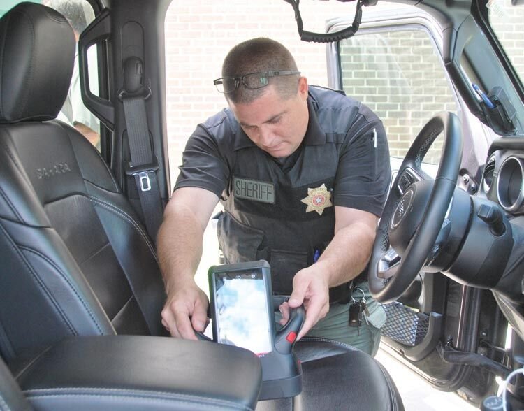 Sgt. David Childress with the McClain County Sheriff&rsquo;s Department locates contraband beneath the driver&rsquo;s seat as he demonstrates the department&rsquo;s new HBI-120 handheld x-ray machine. The $40,000 technology was awarded to the department by Viken Detection Company.