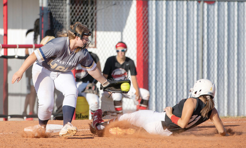 Washington junior Daisy Lampkin slides under the tag of Heritage Hall&rsquo;s third baseman. Lampkin would later score. Washington defeated Heritage Hall 13-0.