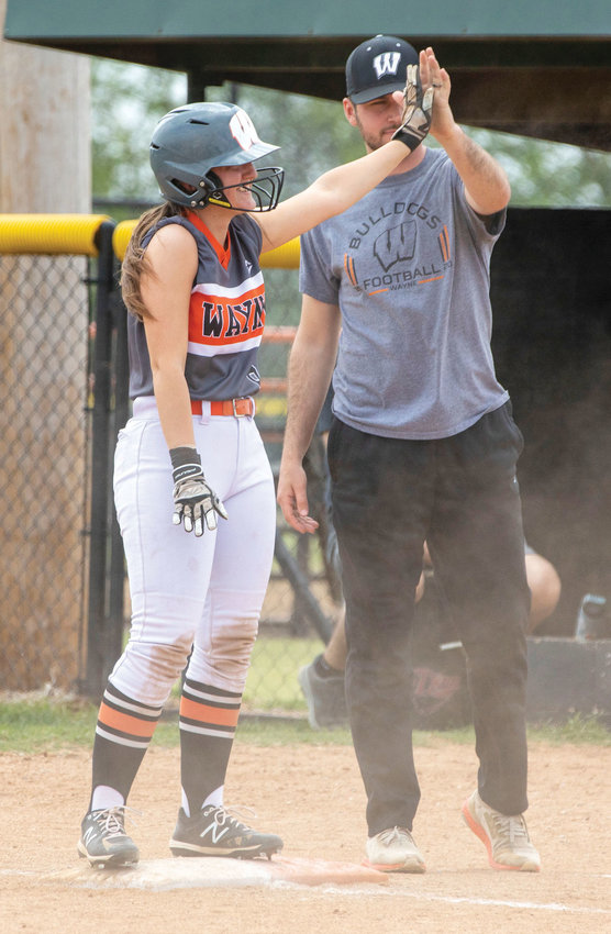 Allison Ryan, a junior for the Wayne Lady Bulldogs, high fives her assistant coach, Jackson Embry, at first base. Ryan and her teammates beat Crescent twice last week to move on to the Regional tournament in Pocola.