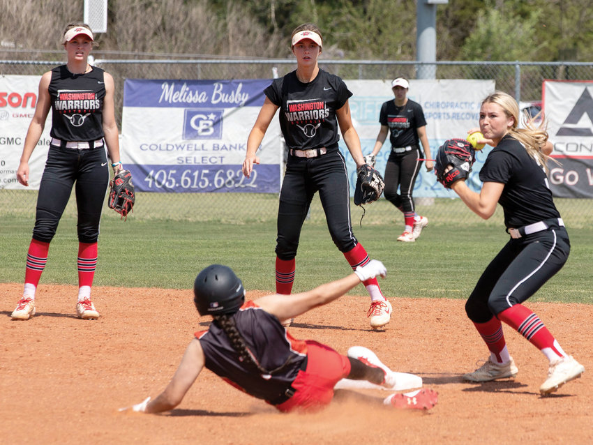 Washington junior Skylar Wells throws to first base after stepping on second while fellow juniors Ellie Loveless and Tinley Lucas look on. The Warriors defeated Riverside 15-0 and 17-0 in two games.