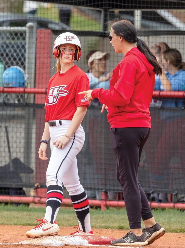Washington freshman Reese Schrader receives instruction from first base coach Jennifer Gay during the Warriors&rsquo; 15-0 win over Chisholm in the Regional tournament.