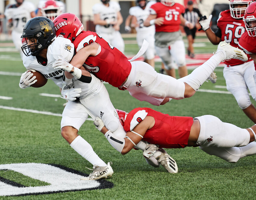 Dragon defenders Kash Guthmueller (20) and Noel Chavez (8) team up to bring down an Alva ball carrier during Purcell&rsquo;s 13-0 shutout win over the Goldbugs Friday night.