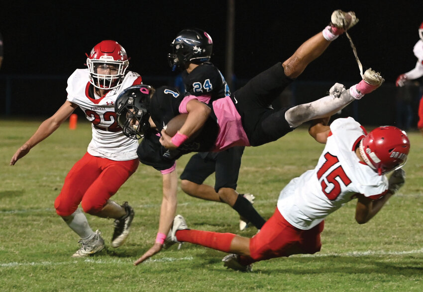 Purcell sophomore Oscar Wren (15) sends a Little Axe ball carrier head over heals as Braylon Francis (22) finishes the play. The Dragons defeated the Indians 42-14.