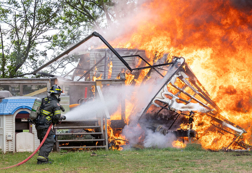 Purcell firefighter Tanner Bell attacks a fire at 22118 220th St. in Washington on Wednesday afternoon. A mobile home and a metal shed were both destroyed by the blaze.