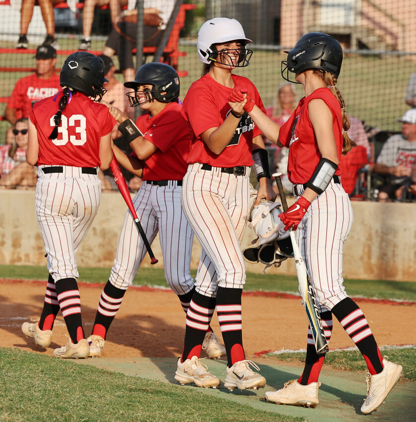 Purcell softball players KK Vazquez and Hannah Whitaker (middle two) are greeted by teammates Mack McKay (33) and Hadleigh Harp after they cross home plate on a Maica Martinez single in a Super Regional game. Purcell beat Cache 3-1 and 2-0 to advance to the State tournament at Devon Park.