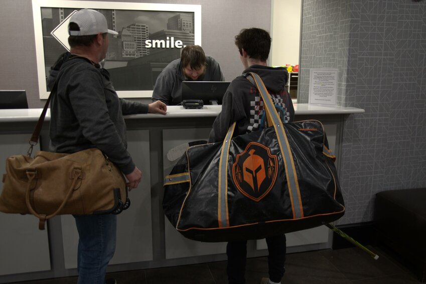 Oklahoma City high school hockey player Brent Bailey, right, and his father, Bill Bailey, check into an Olathe, Kansas, Hampton Inn in February.