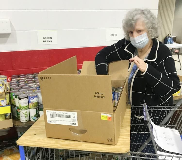 McClain County Operation Christmas volunteer Carolyn Harrison fills a food basket during preparation for Friday’s distribution of food and gifts.
