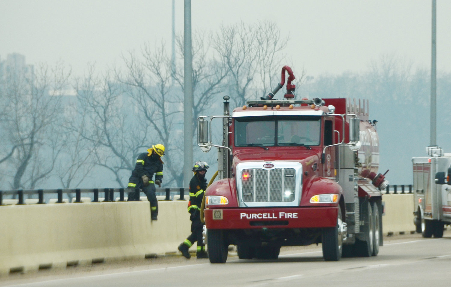 Purcell firefighters prepare to cut off an out-of-control wildfire from atop the James C. Nance Bridge last week amid high winds and dry conditions.