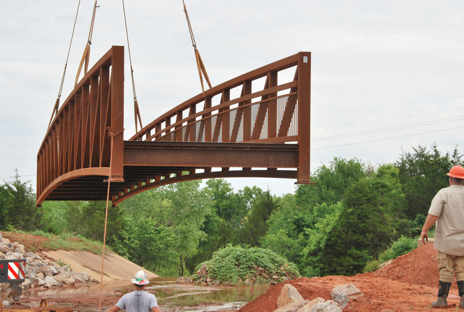 The new walking bridge over the spillway at the Purcell City Lake was moved toward its resting spot by a huge crane provided by Brady Crane Services. According to City Manager Dale Bunn the rental on the 70’ crane was $6,500.