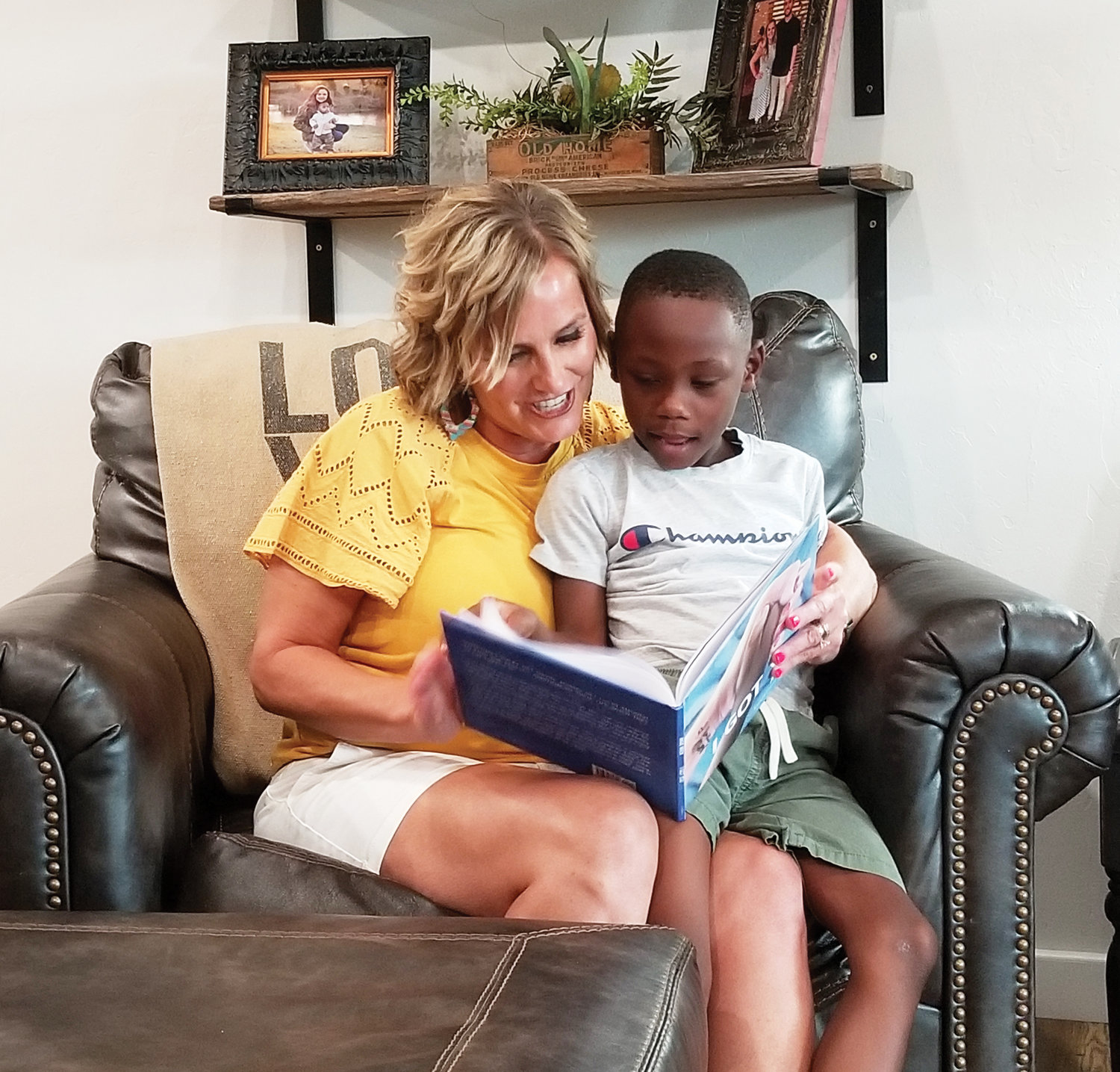 Five-year-old Devin Wren sits in his mother’s lap and reads the book Angie Wren wrote about  the Wrens adopting Devin as an infant. The children’s book, “I Got You,” is illustrated by Purcell High School art teacher Jon Corea. Angie Wren teaches seventh grade English at Purcell Junior High School.