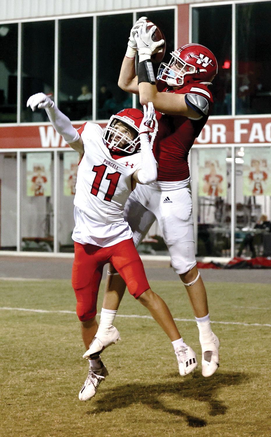 Washington sophomore Nate Roberts catches a touchdown pass over the top of Purcell’s Ty Jaspersen Friday night during the Warriors’ 40-7 win over the Dragons.