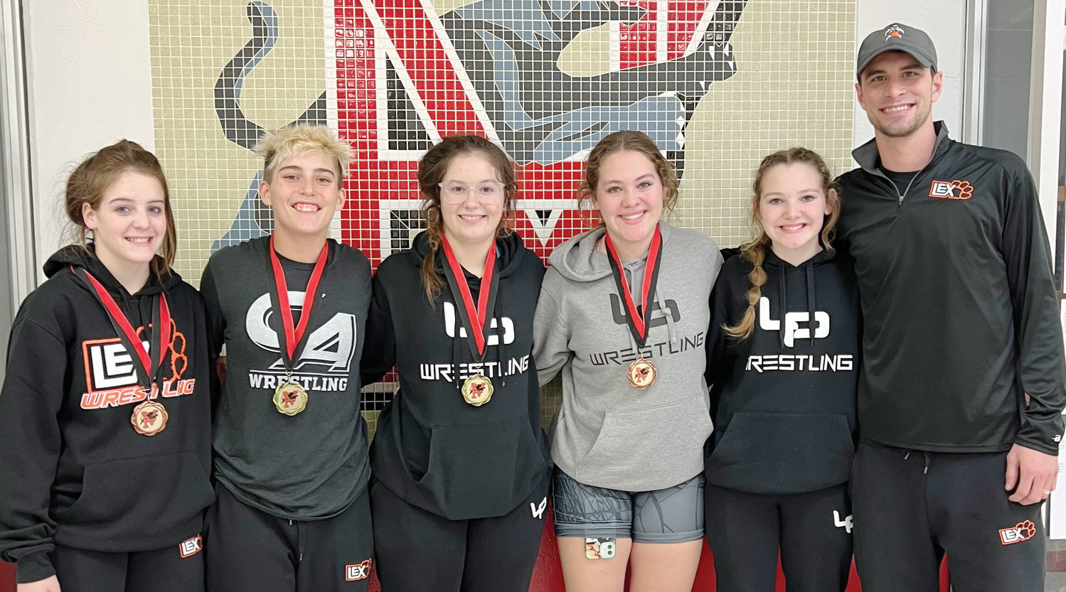 The Lexington girls were crowned tournament champions at the recent Pauls Valley wrestling tournament. From left are Bailey Forbes, Izzy Pack, Cilee Turner, Elexa Collins, Mo Collins and coach Mike McKay. Holding the trophy are Elexa and Mo.