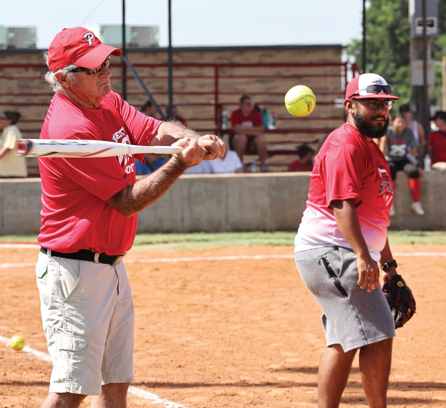 Former Purcell softball and baseball coach Mike Robinson, who recently joined the Purcell All Sports Hall of Fame, hits balls during the annual Purcell Dragon Alumni Softball Game on Saturday. Softball coach Joseph Franco, right, caught in for the legendary Robinson.
