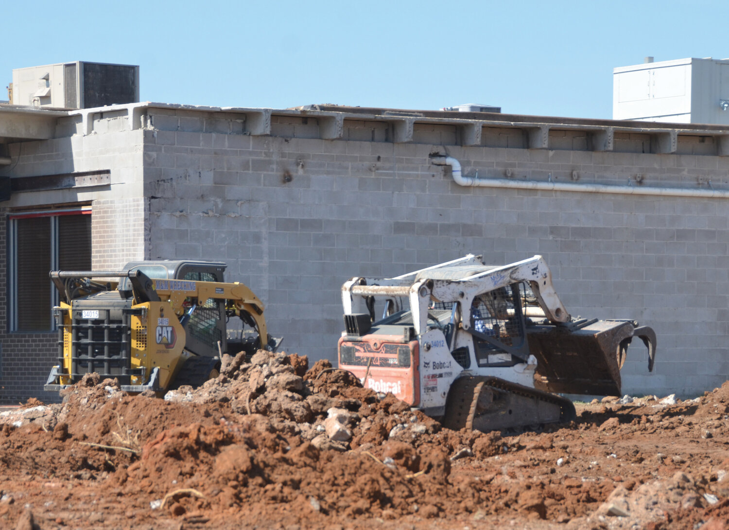 A pair of Bobcats pick up the huge chunks of concrete to load onto trucks for hauling off as demolition continues at Mid-America Technology Center,