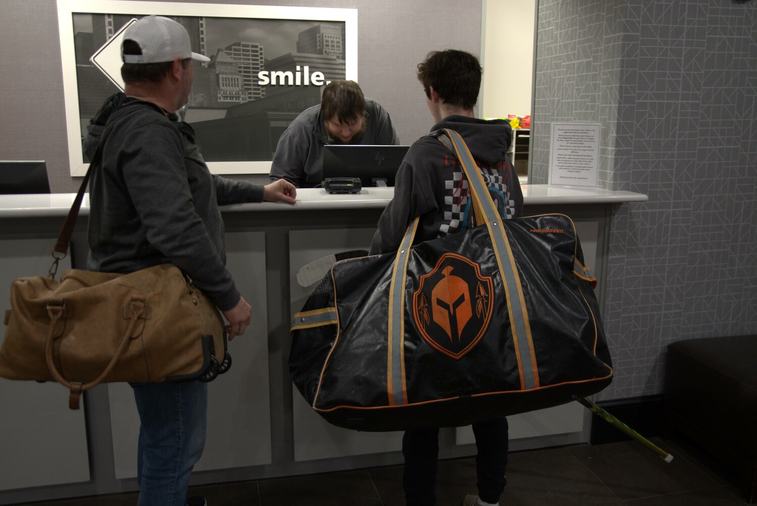 Oklahoma City high school hockey player Brent Bailey, right, and his father, Bill Bailey, check into an Olathe, Kansas, Hampton Inn in February.