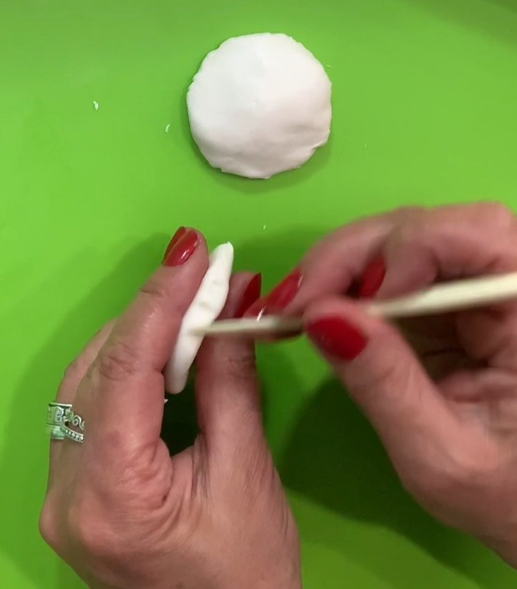 Make the top and bottom hamburger buns out of white fondant. Add texture with a clay tool.