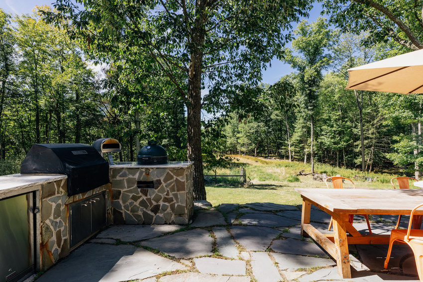 The outdoor kitchen features a gas grill, a mini-fridge and a smoker.