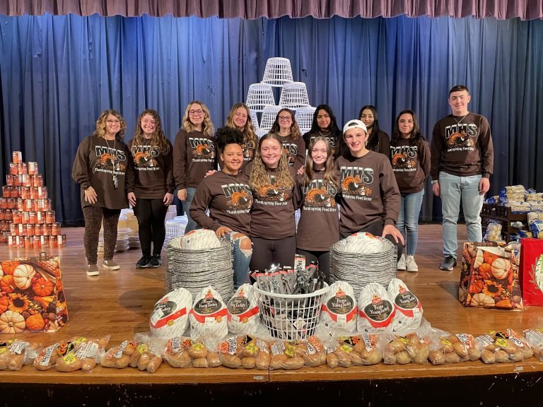 The food drive committee and Collura pose by a mountain of donations...