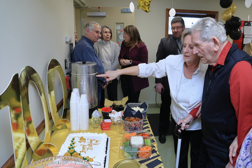 Nancy Zafiris of the Adult Daily Living Center points to the big 100 as the man of the hour, Raymond “Ray” Naholnik, takes it all in and admires his birthday cake...