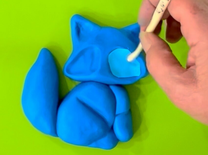 Roll out lighter-colored fondant thinly. Snip into shapes that will fit into the eye sockets, ears, and chest area. Add each piece and smooth out with ball and cake tools. Trim as needed with an X-Acto knife...