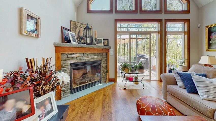 A stacked-stone gas fireplace anchors a corner of the living room, next to a sliding glass door leading to the back deck.