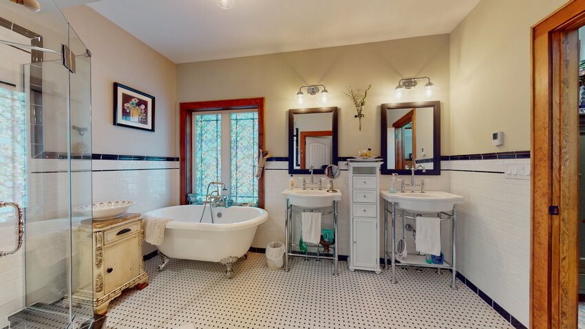 The primary suite bathroom boasts a clawfoot tub and twin sinks as well as that spectacular shower.
