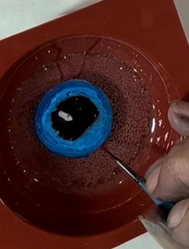 Paint the eyeball on the isomalt with edible colors. Pour on another layer of clear isomalt. Let harden. Paint in details on the eye—veins, etc. Pour on another layer of isomalt. Let harden...
