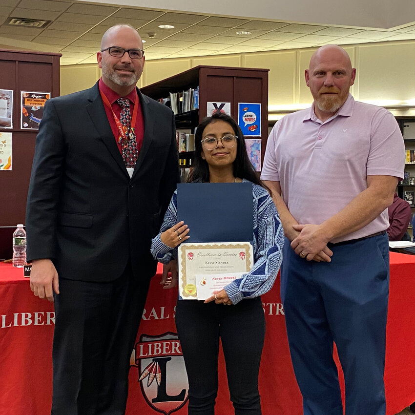 Excellence in Service Award winner Keysy Mendez poses with Superintendent Dr. Patrick Sullivan, left, and Board President Matthew DeWitt, right.