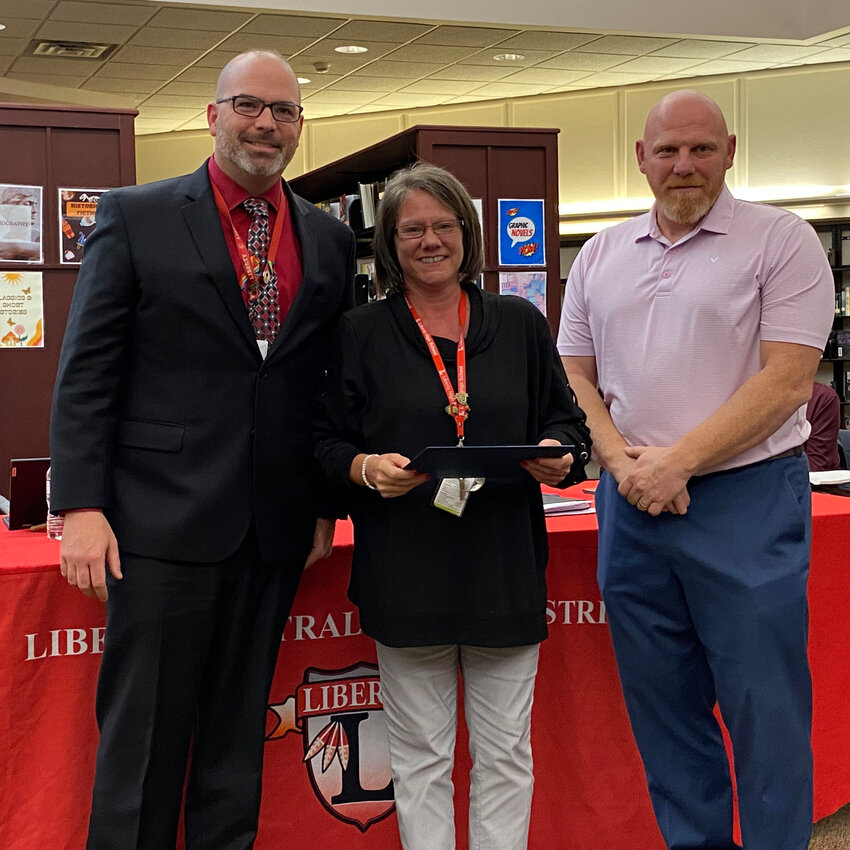 Excellence in Service Award winner Kelli Arpino, center, poses with Superintendent Dr. Patrick Sullivan, left, and Board President Matthew DeWitt, right.
