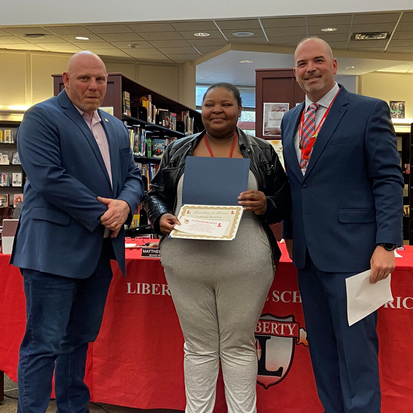 LaTrease Burdick, center, is pictured with Liberty school board president Matthew DeWitt, left, and superintendent Dr. Patrick Sullivan at right.