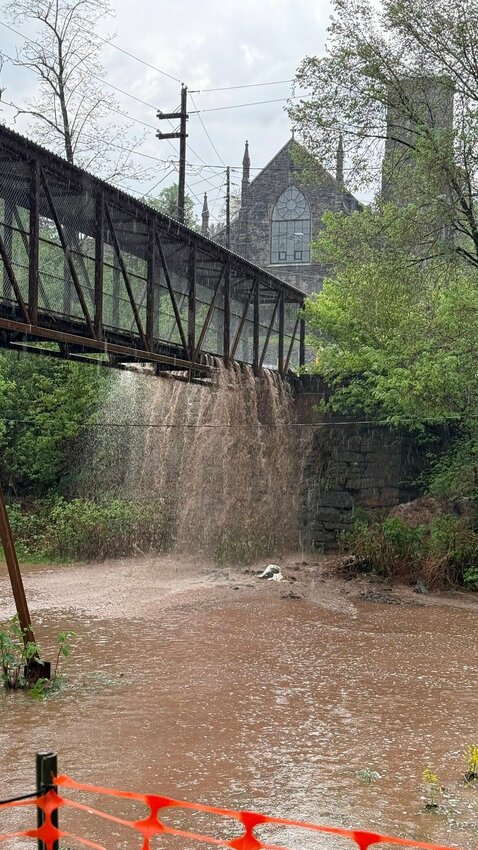 Picture from Alert Hook & Ladder Co. #2 - Honesdale Fire Dept. Facebook page: Floodwater falls off the 5th Street pedestrian bridge, with St. John's Church in the background, during the May 6 flooding in Honesdale.