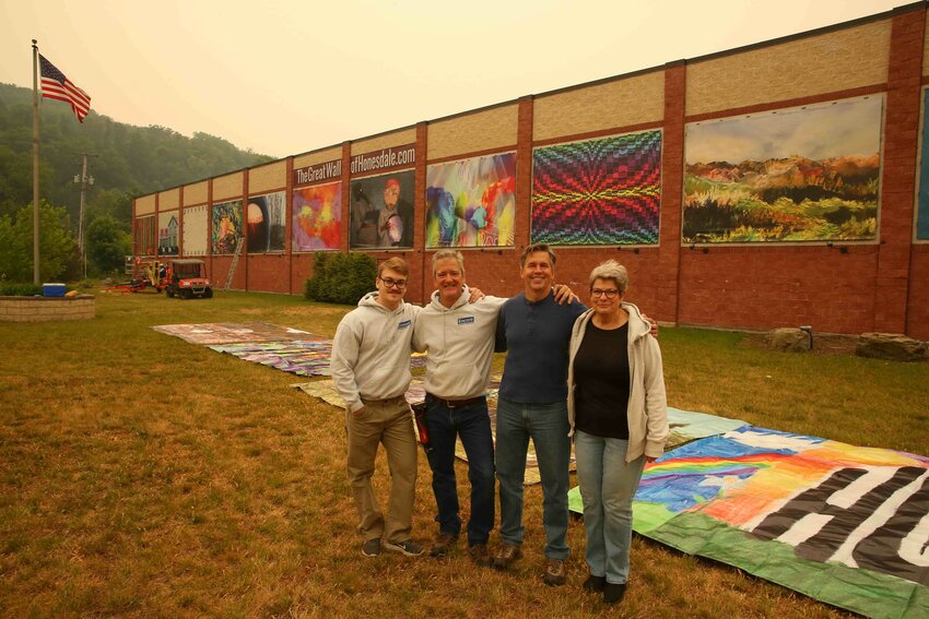 Standing under smoky skies, Christ Khoury, left; Glenn Khoury; Dave Janiec; and Phyllis Chekenian celebrate the new Great Wall of Honesdale.