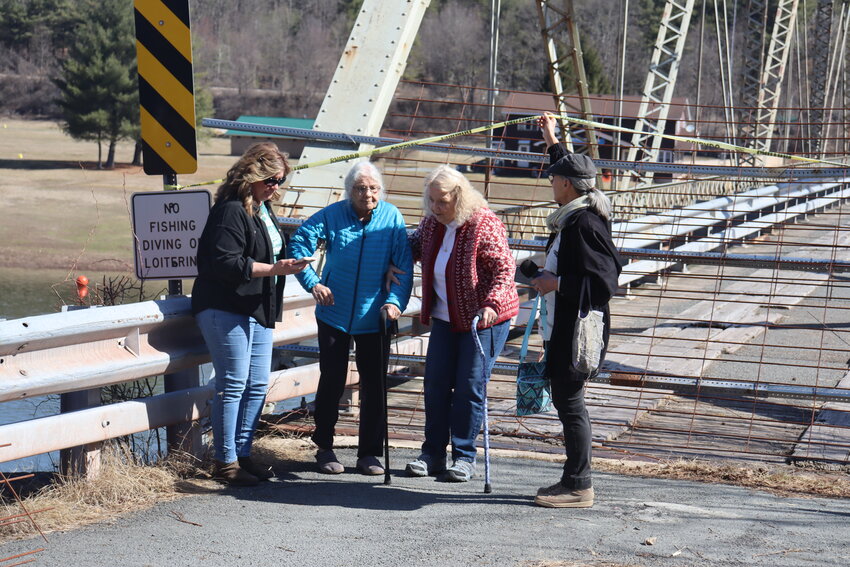 Sheila Dugan, in blue, is helped away from the Skinners Falls Bridge on Wednesday, March 19.