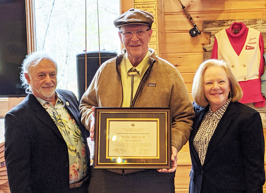 Ted Patlen (left) presents the Catskill Fly Fishing Center and Museum 2021 Hall of Fame award to inductee Paul Bruun. At right is Jean Bruun, Paul&rsquo;s wife.