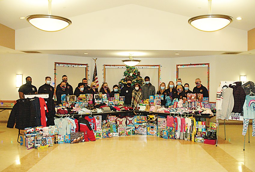 Members of the Monticello Fire Department&rsquo;s volunteer firefighters, professional firefighters, and the department's Auxiliary, alongside 1st Way Life Center&rsquo;s Annette J. Rien, and Monticello High School Seniors and volunteers Jack Rien and Rohan Patrick, displaying the donated clothes and toys.