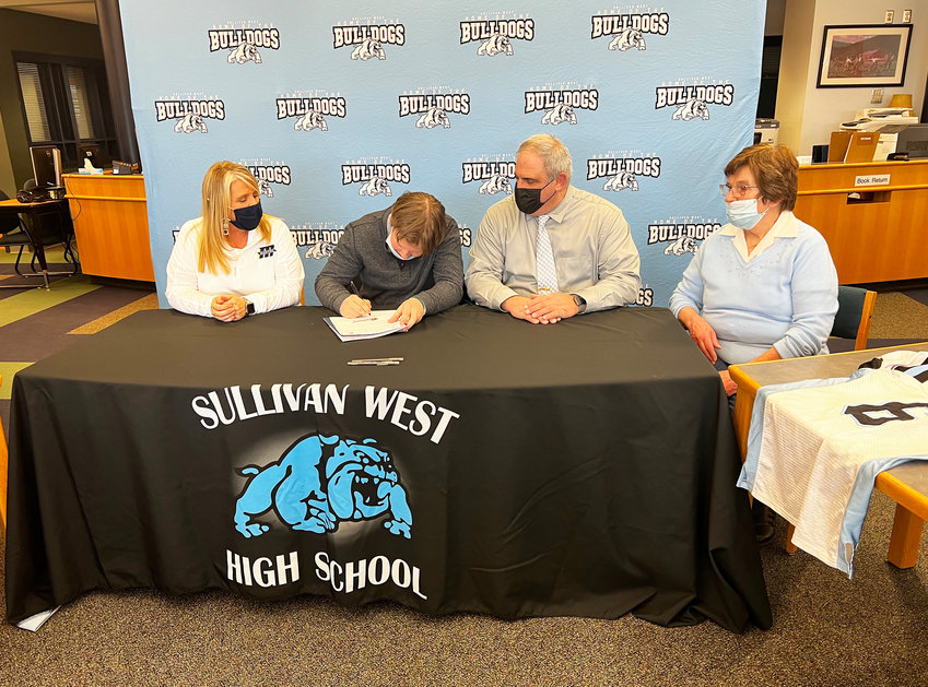 Sullivan West&rsquo;s Gavin Hauschild pens the Division III Celebratory signing form making it official that he will be attending Massachusetts Maritime Academy to play football and pursue his intended path towards a career in Emergency Management. He is flanked by his mother Dawn, his father John and grandmother Barbara.