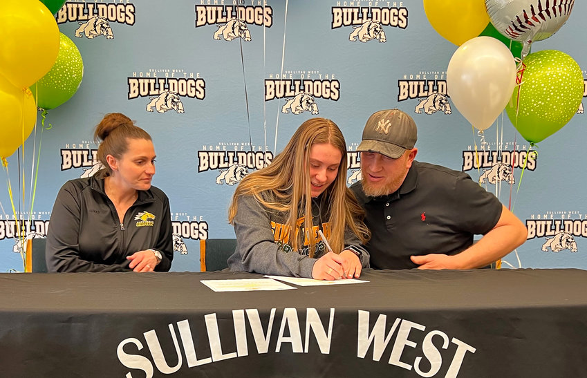 Riley Ernst signs her Celebratory Letter agreeing to attend SUNY Delhi and participate in women&rsquo;s basketball and softball. She is flanked by her mom Crystal and her dad Jeremy.