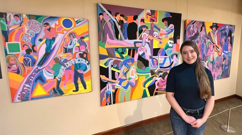 Julia Fell, Curator of Exhibits at The Museum at Bethel Woods stands before paintings by Julie Lomoe, who showed off her art work at the 1969 Woodstock Music &amp; Art Fair.