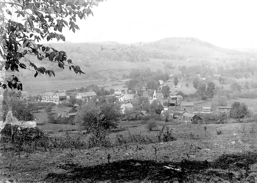 Vintage view from C. Spielmann Rd.:   This photo of Youngsville predates the building of the old firehouse and St. Francis R.C. Church. The German Reformed Church (now the United Reformed Church) can be seen by its spire near the center-right of the photo. The now non-existent corner store (where the Youngsville Fire Department&rsquo;s electronic sign now gives the time), is the long, tall building on the left, situated on the corner of North road (Shandelee Road) and the state route that bisects the hamlet. It appears here that Panther Rock Brook once traveled the way of what is now Tremper Lane. The photographer unfortunately is unknown.
