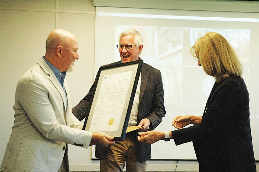 SUNY professor of 37 years, Arthur Riegal, left, received a framed copy of the resolution passed by the Board of Trustees which granted him Emeritus status from Dr. Terry Hamlin, right, and President Jay Quaintance, middle.