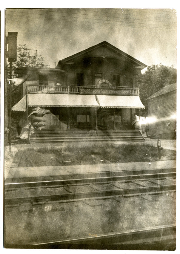 Ghostly reflections:      In the spirit of Halloween, this image of the Globe Hotel in Callicoon is superimposed by a reflection of the photographer, indicating that the camera was inside the depot when the image was exposed. Note the reflection of a hand with a ring (and handkerchief or rag) at left. The earliest operator of the Globe Hotel that we could find was William E. Batsford, who kept the hotel in 1874. In 1898, Cris Jardin sold the hotel to a man named Kothe.