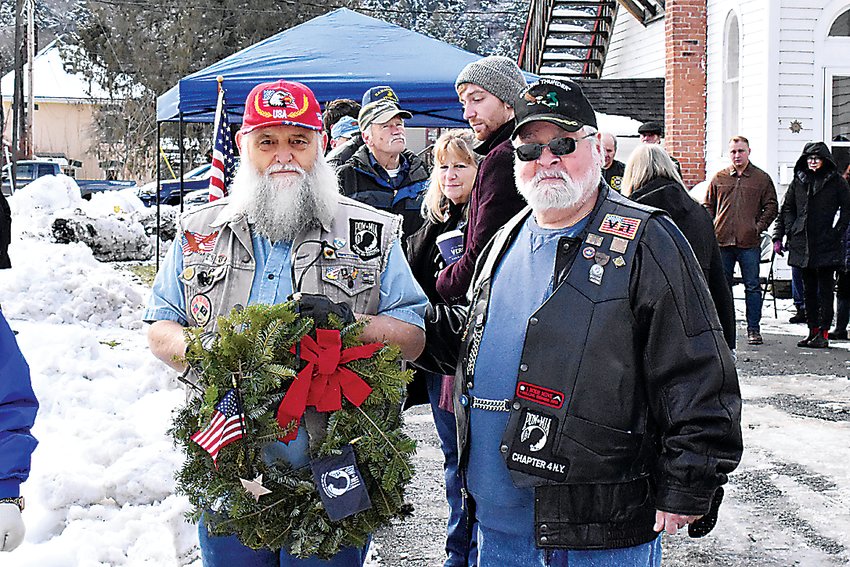 Jim Sennett (left) and Vinnie Pierce from Rolling Thunder prepare to hang a wreath in honor of the 93,129 United States Servicemen from all branches whose last known status was either Prisoner of War or Missing in Action.