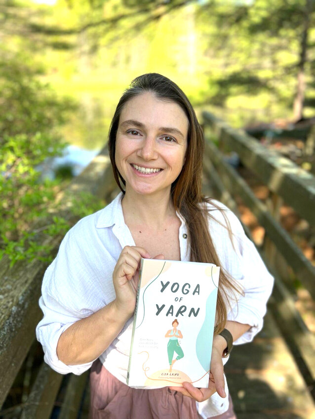 Liza Laird holding her book titled &ldquo;Yoga of Yarn.&rdquo;