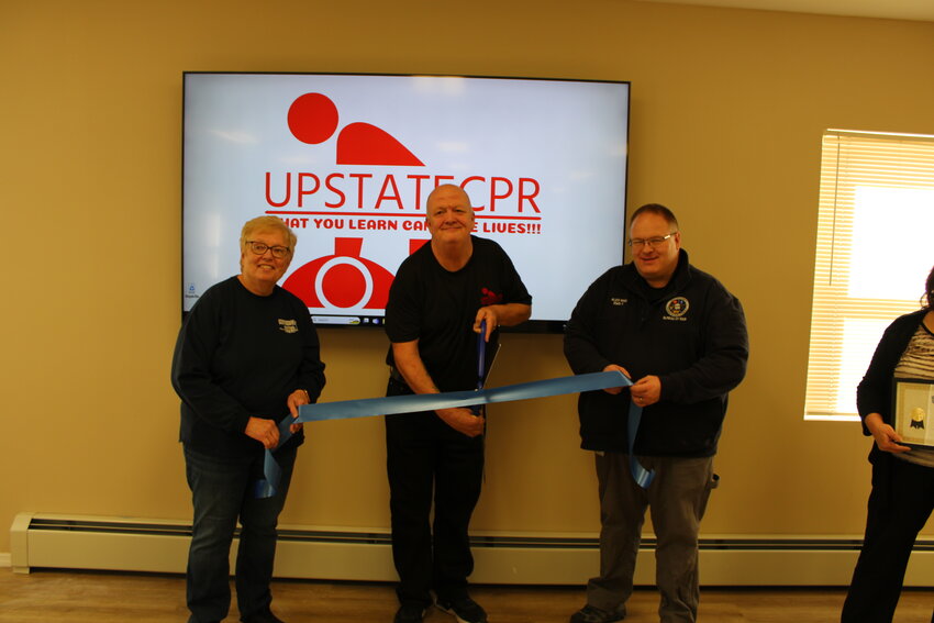 From left, Ann Bivins, Norman Prentice and Alex Rau cut the ribbon on Friday.
