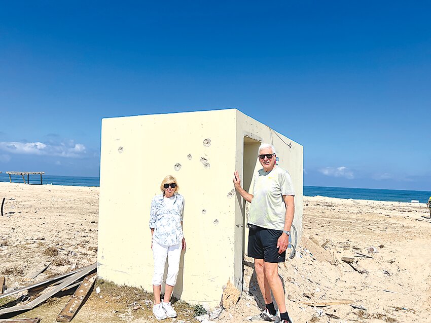 Marjorie and Phillip Jacobs stand next to the shelter on Zikim  beach to which 15 teenagers ran into to escape Hamas terrorists who had waded ashore, and in which they were killed.